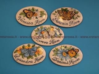 cod.art: nc112a - Mattonella ovale in ceramica cm 8,5 x13 circa dipinta a mano con decoro farfalle e scritta personalizzata. 